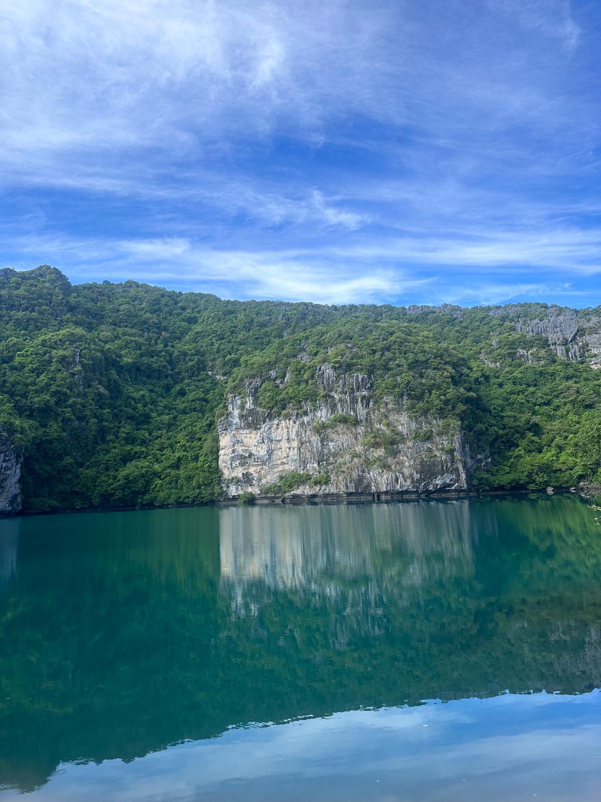 Erleben Sie die vollkommene Ruhe einer versteckten, smaragdgrünen Lagune, in der sich dschungelbedeckte Kalksteinklippen im spiegelglatten Wasser verlieren. Dieses unberührte Naturparadies lädt dazu ein, die Seele baumeln zu lassen und unvergessliche Momente fernab des Alltags zu sammeln. Gehen Sie mit uns auf Entdeckungsreise und lassen Sie sich von dieser magischen Kulisse verzaubern.